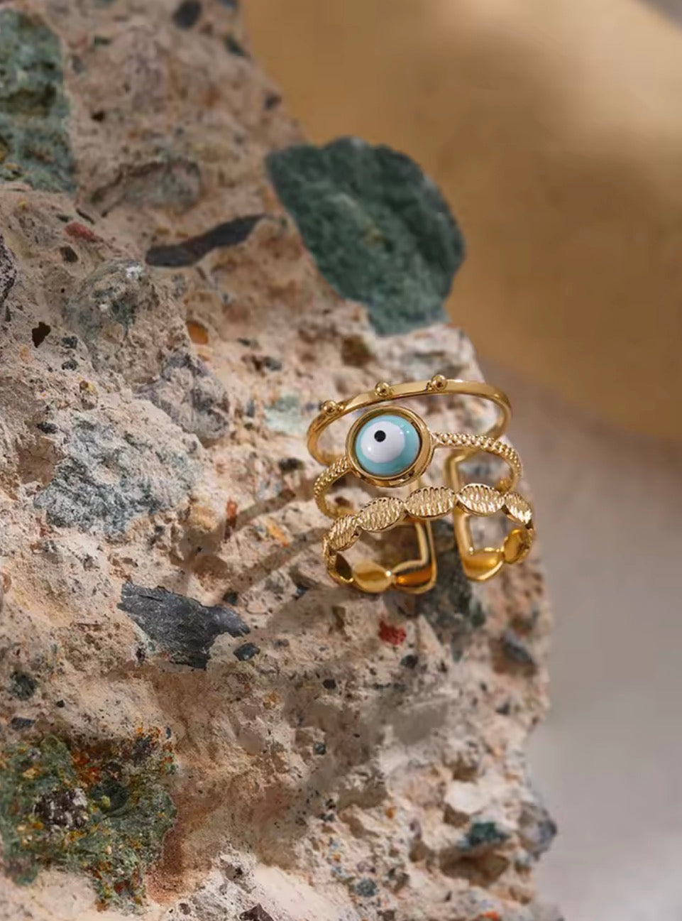 Evil Eye 3-Layer Ring on textured rock — showing layered gold bands and turquoise evil eye stone detail