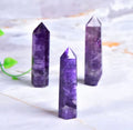 Natural amethyst crystal point towers in three sizes on marble surface